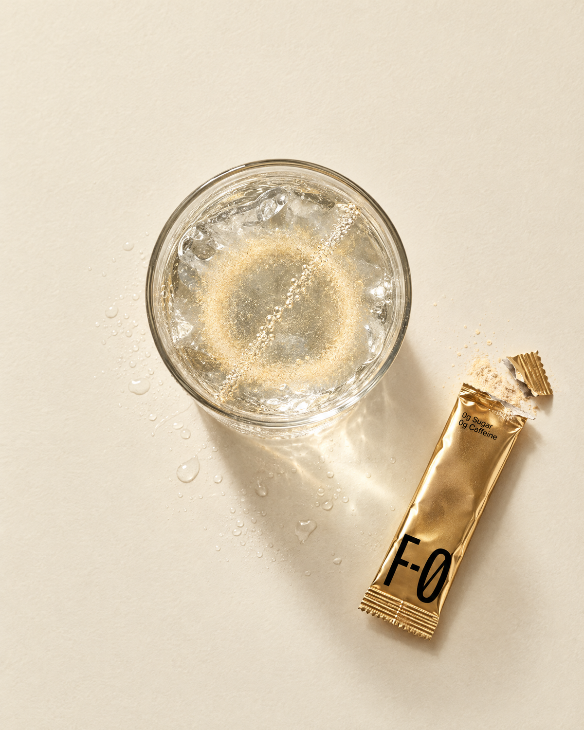 Glass of cold water with F-0 powder dissolving into a ring, gold stick beside it